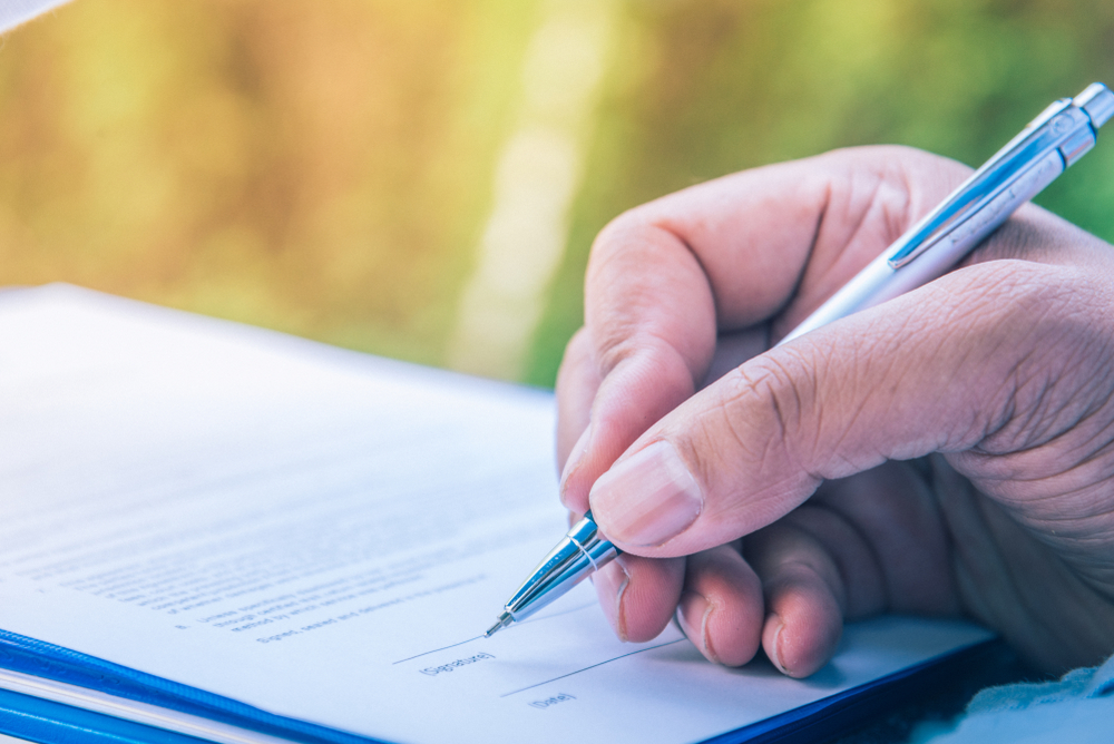 Close-up of a man's hand as he signs a power of attorney document.